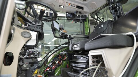 Von außerhalb einer Traktor Kabine, schaut man ins innere und sieht sehr viel Technik, da unterhalb dem Lenkrad die Verkleidung fehlt und hinten rechts oben ein neues Display und zwei Check Control hängen.