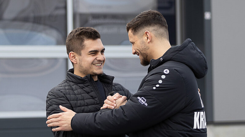 Kevin Arnold klatscht gerade einen weiteren Mann namens Ardian Krasniqi ab und umarmen sich fast dabei. Beide strahlen mit einem lächeln.