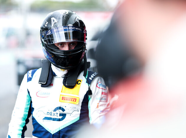 Luca Arnold Rennfahrer für das Team Arnold NextG steht in seinem Rennanzug mit schwarzem Helm und schaut nach rechts.