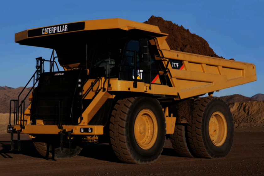 Ein gelber Caterpillar Mining Schwerlast-Kippwagen, der bei blauem Himmel voll gefühlt mit Erde ist.
