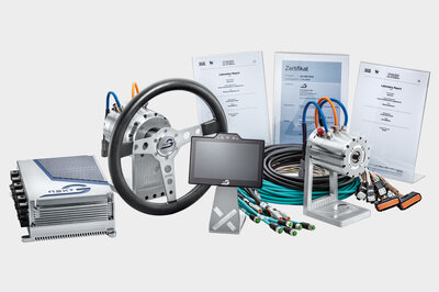 Ein Gesamtbild aller Kompunenten von NX NextMotion, links das NX NextMotion, dann ein Force Feedback Motor mit Lenkrad, ein Touch Display, Kabelsätze und eine Road Weehl Aktuator. Im Hintergrund stehen noch drei Zertifikate.