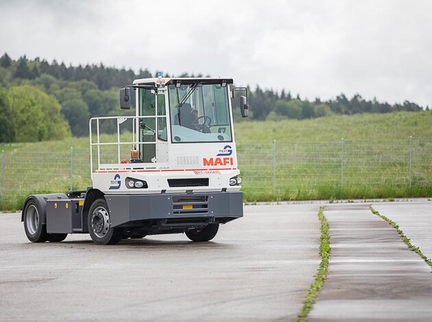 Ein autonom fahrender Terminal-Traktor der Firma MAFI, umgebaut mit NX NextMotion, bewegt sich fahrerlos über einen Übungsplatz.