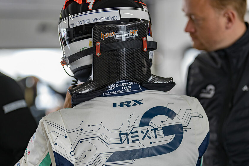 Ein Rennfahrer in einem Arnold NextG Rennanzug und Helm steht mit dem Rücken zur Kamera. 