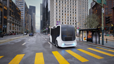 Ein autonomer Mover hält an einer Bushaltestelle in einer mehrspurigen Großstadtstraße.