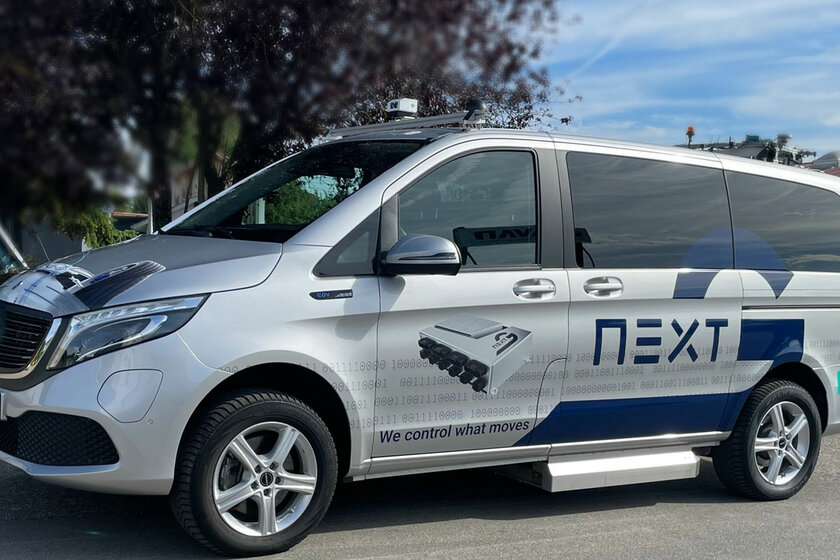 Ein gebrandeter Arnold NextG Mercedes EQV in Silber, steht bei blauem Himmel vor einem Baum.