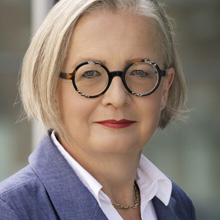 Eine freundlich lächelnde Frau mit Brille die Anke Leuschke ist und deine Ansprechpartnerin ist.