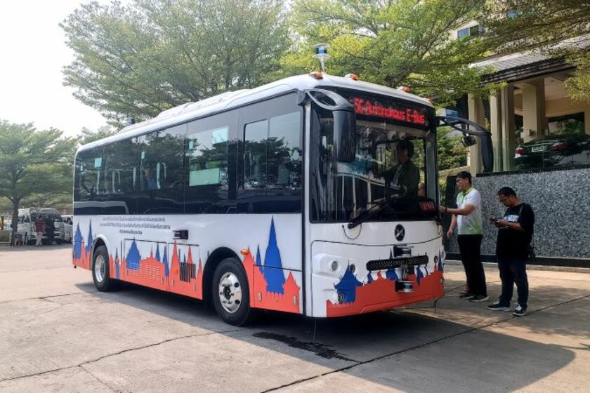 Ein weiß roter Bus steht am Straßenrand bei strahlendem Sonnenschein. Ein paar Menschen stehen auf dem Bürgersteig neben dem Bus.