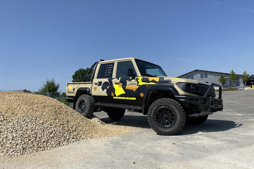 Ein Toyota Landcruiser mit Doppelkabine für Untertagebau/Bergbau in braun mit schwarz und neonfarbenen Highlights, steht mit dem rechten Hinterrad auf einem Schotterhaufen.