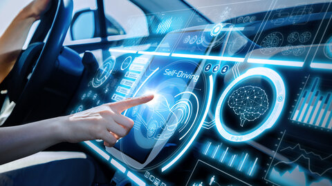 Ein futuristisches digitales Amaturenbrett eines Autos mit einem Lenkrad ganz links. Auf das digitale Display drückt eine Hand mit dem Zeigefinger drauf.