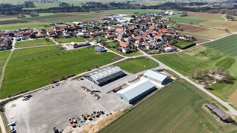 Eine Luftaufnahme von Aichelau Pfronstetten, von Ehestetten kommend. Am unteren Bildrand erkennt man die Hallen des Next Mobility Campus und im Hintergrund Aichelauer Wohnhäuser.