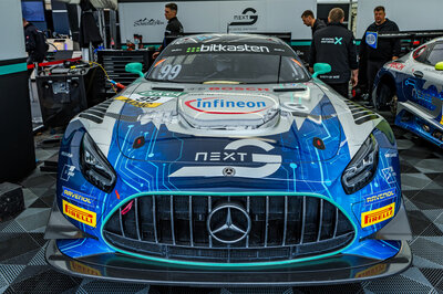 Ein Mercedes GT3 von Arnold NextG frontal fotografiert in seiner Box. Im Hintergrund stehen mehrere Mechaniker.