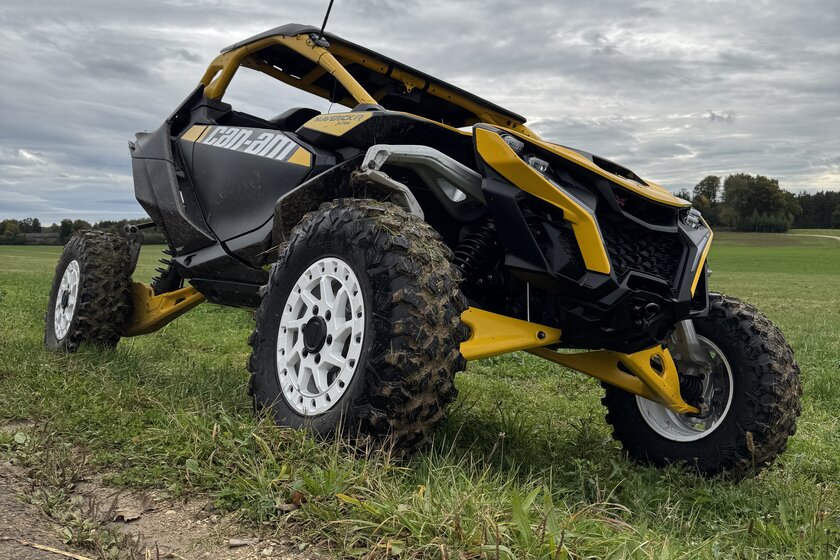 Ein gelb-schwarzer Buggy steht schräg auf einer hügeligen Wiese.