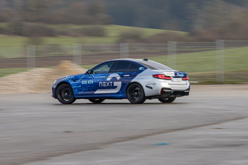 Ein silber blaues Auto mit einem Arnold NextG Logo fährt auf einem Platz schnell herum. Der Hintergrund ist unscharf.