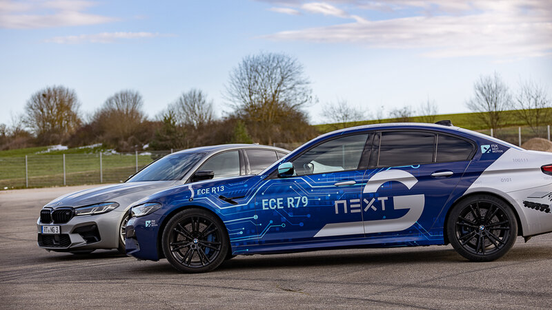 Zwei BMW M5 stehen hintereinander auf einem Übungsplatz. Der hintere BMW M5 ist ein silberner normaler BMW. Der Vordere ist ein von uns umgebauter BMW M5 mit NX NextMotion Force-Feedback-Technologie