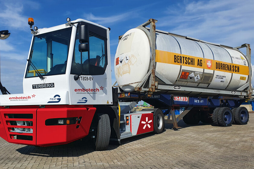 Ein Terminal Traktor von terberg steht mit einem runden Anhänger auf einem Platz bei blauem Himmel.