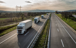 Mehrere Lkw fahren im perfekten Abstand zueinander als Platooning Lösung auf der rechten Spur einer Autobahn.