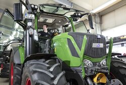 Ein hellgrüner Traktor, umgerüstet mit NX NextMotion, wird von einem Techniker in der Werkstatt getestet, während er in der Kabine sitzt.
