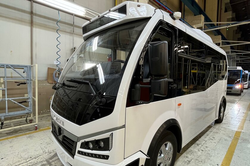 Ein weißer Bus steht in einer Lagerhalle. Weitere Fahrzeuge stehen mit abstand dahinter.