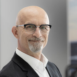 Ein freundlich lächelnder glatzköpfiger Mann mit Brille der Mathias Koch ist un dein Ansprechpartner ist.
