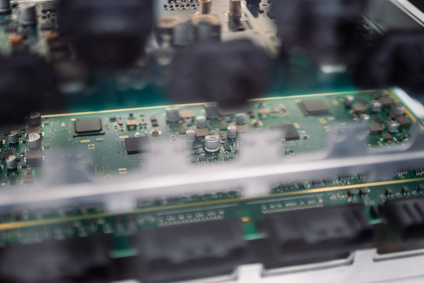 Ein Bild welches sehr viel unschärfe im Vordergrund durch schwarze stecker hat, versteckt fast komplett eine grüne Platine die im Hintergrund scharf zu sehen ist.