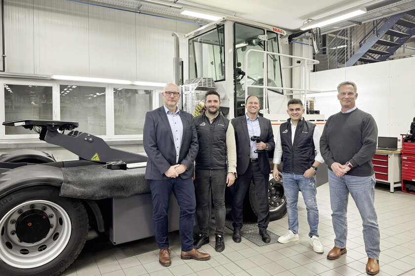 Mehrere Männer stehen aufrecht vor einem Terminal Traktor in einer Werkstatt.