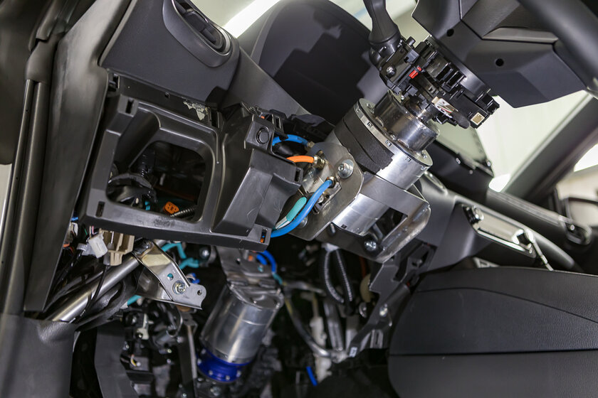 Ein aufgeschraubtes Lenkradgehäuse, welches komplett umgebaut worden ist. Lenksäule weg, Force Feedback Motor, am Lenkrad, von NX NextMotion rein. Mehrere bunte Kabel wurden neu Verlegt.