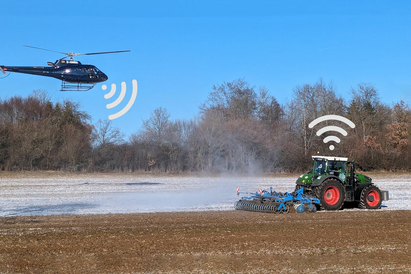 Auf einem Feld fährt ein Traktor mit Anbaugerät. Etwas hinter dem Traktor fliegt ein Helikopter, beide haben Wlan zeichen über sich.