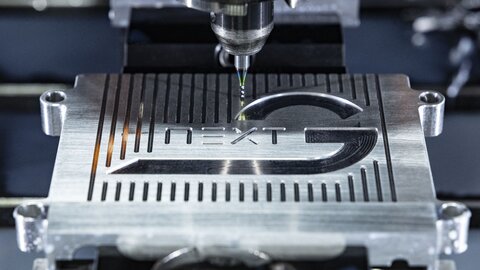 In ein Stück Metall wird ein NextG Logo gefräst.